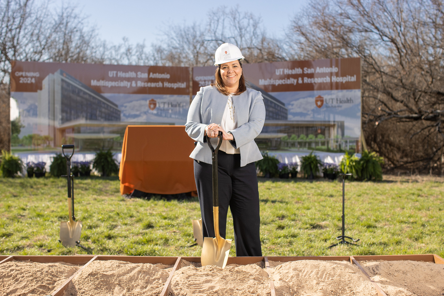 Woman poses with hard hat and shovel at groundbreaking Multispecialty and Research Hospital