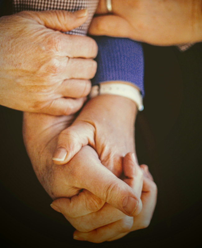 elderly couple holding hands