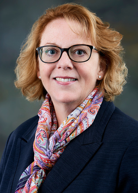 photo portrait of a woman in a dark jacket wearing a paisley scarf