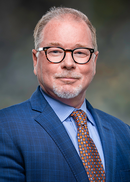portrait photo of a man wearing glasses in a blue suit