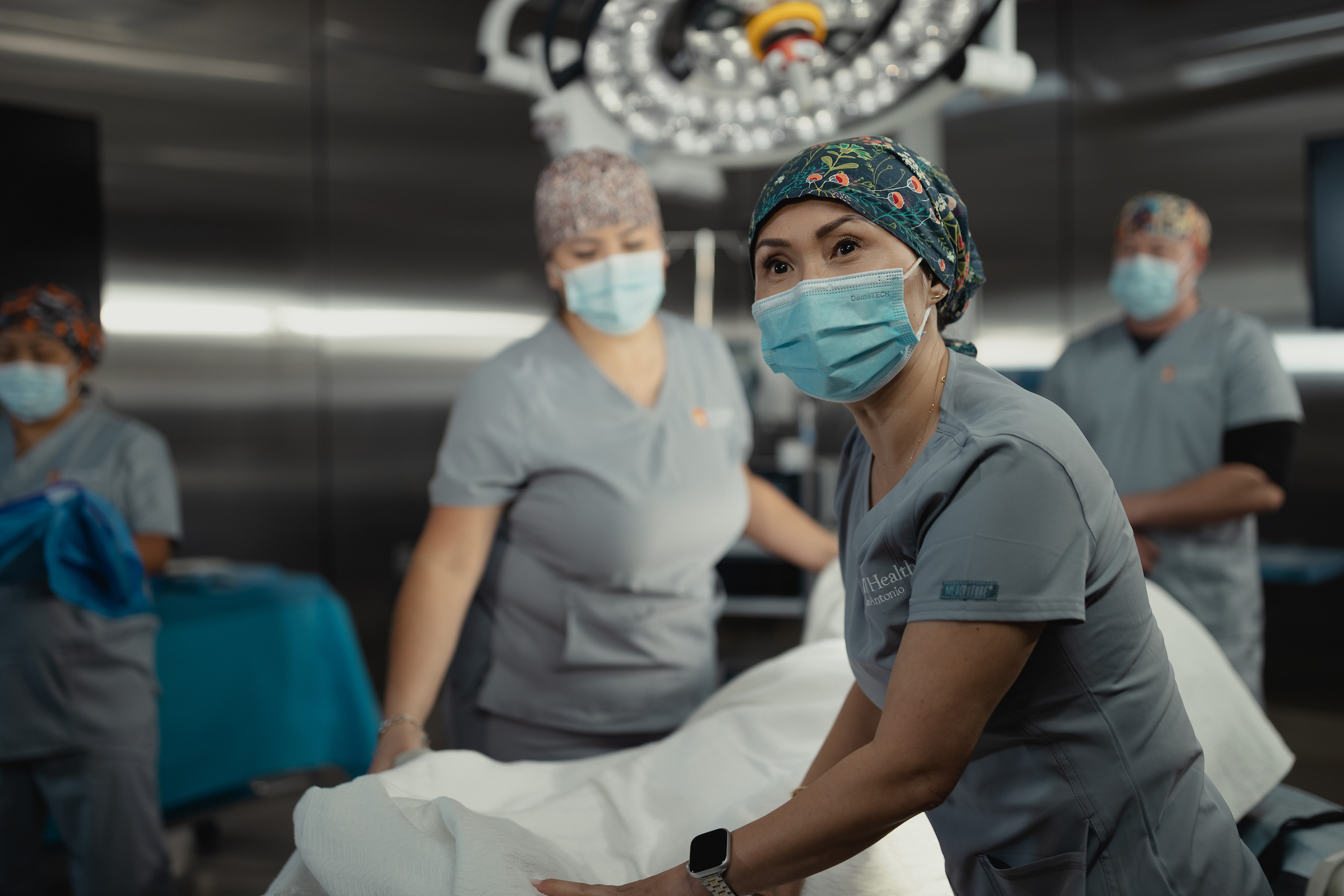 Surgical nurse in scrub cap and mask reviews monitor