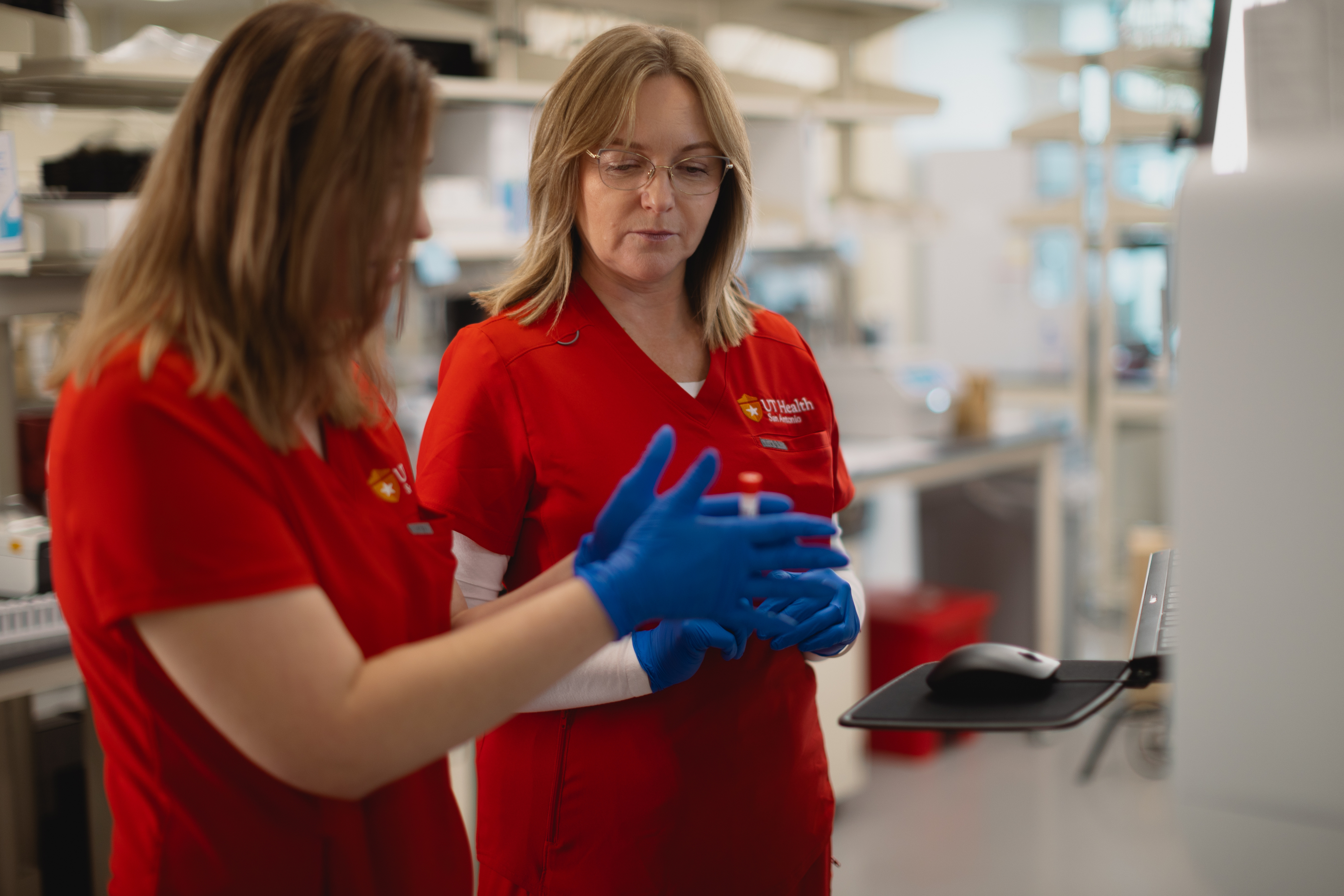 Two lab techs evaluate a blood sample