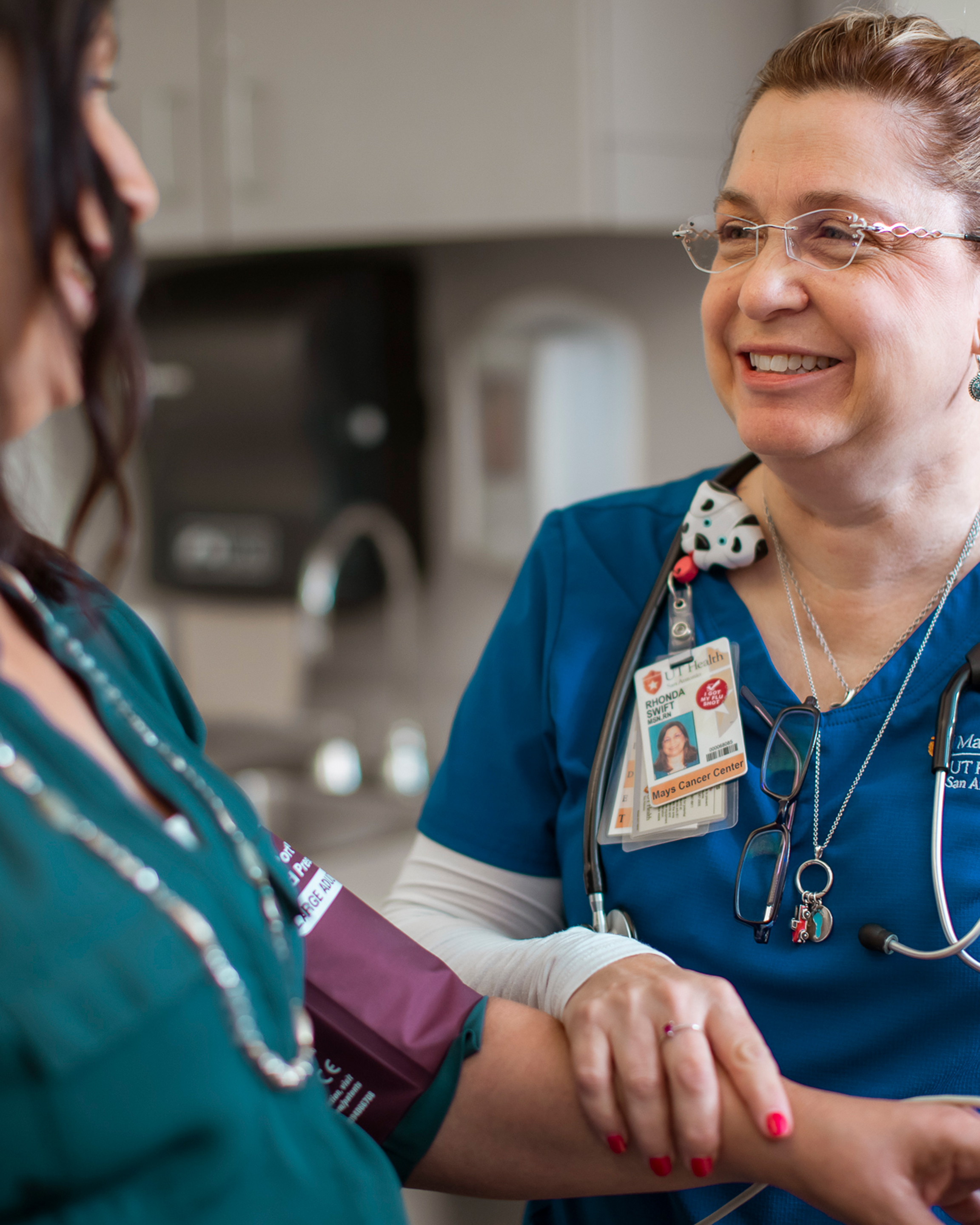 a nurse smiling at a patient while measuring blood pressure