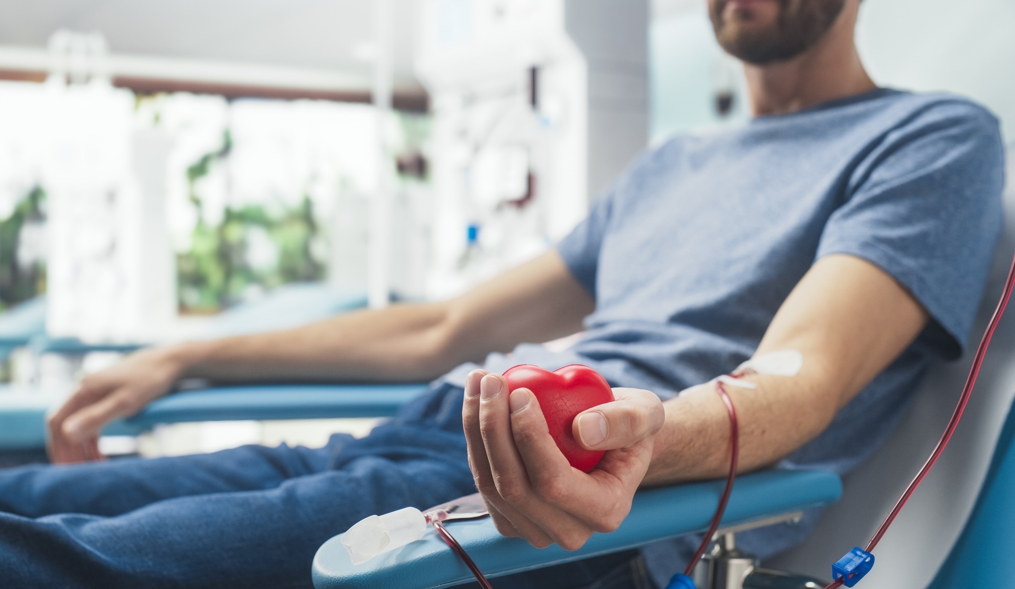 Man donating blood squeezing red stress ball