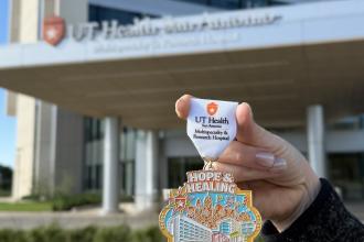 The hospital Fiesta medal for 2026 being help in front of the hospital entrance