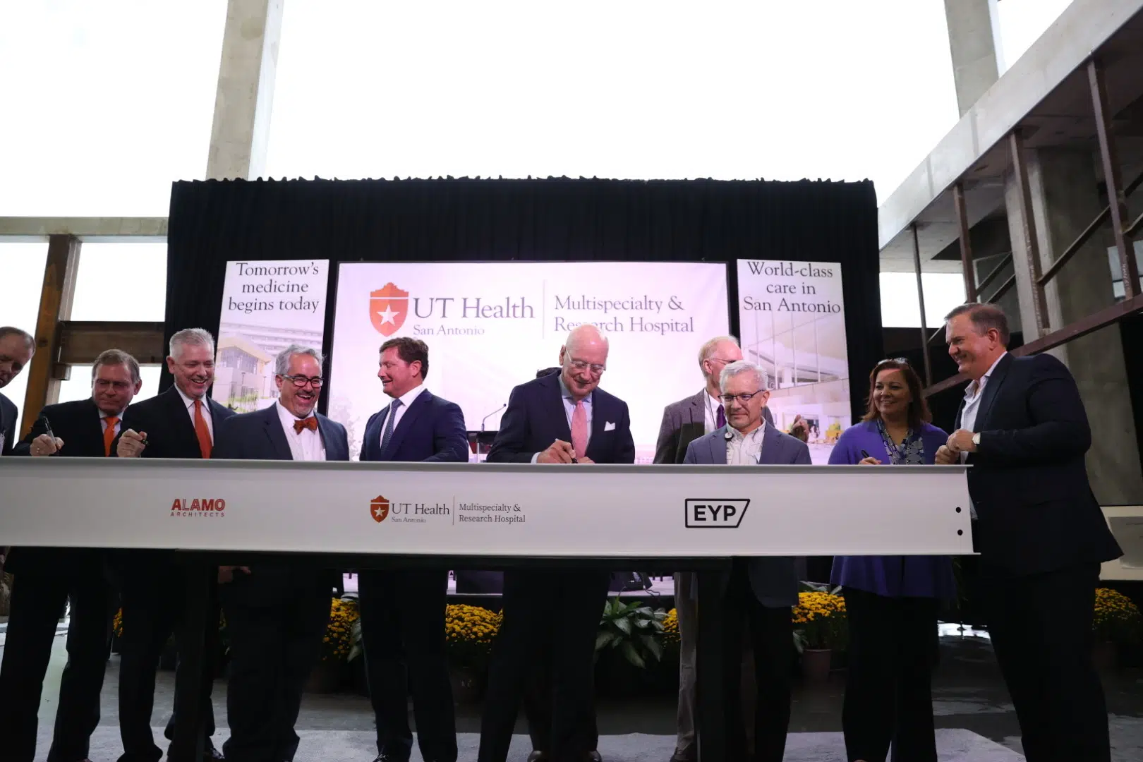 UT Health San Antonio leaders signing the iron beam that will be placed atop the new hospital building.
